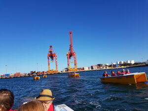 Yellow boats on the Swan River near Fremantle. Large cargo loading cranes in the background.