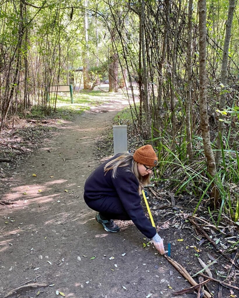 Person crouched in a national park with a tape measure