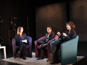 Three people sitting in chairs speaking as part of a panel